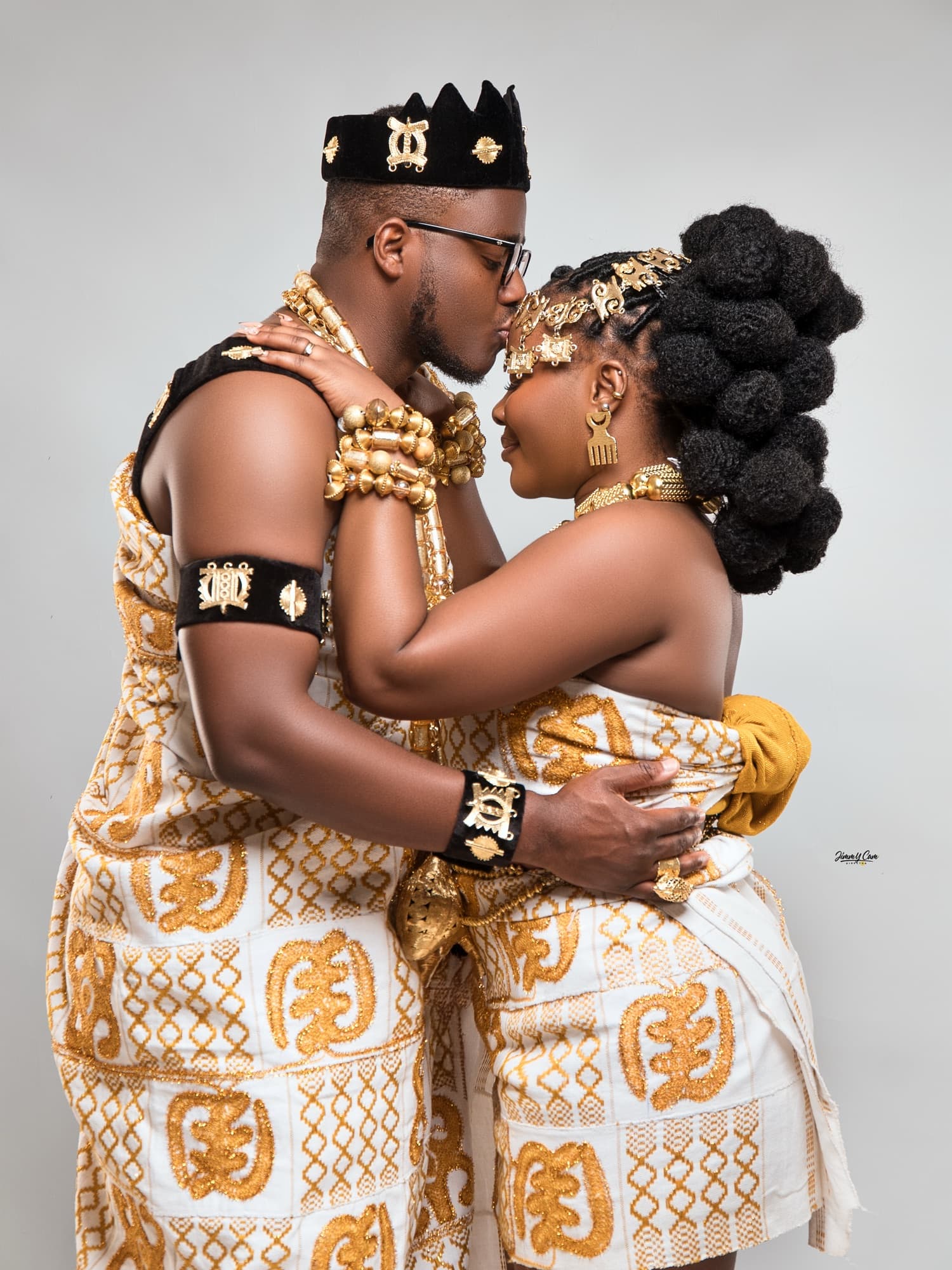 Couple en kente blanc et or, front contre front, séance en studio